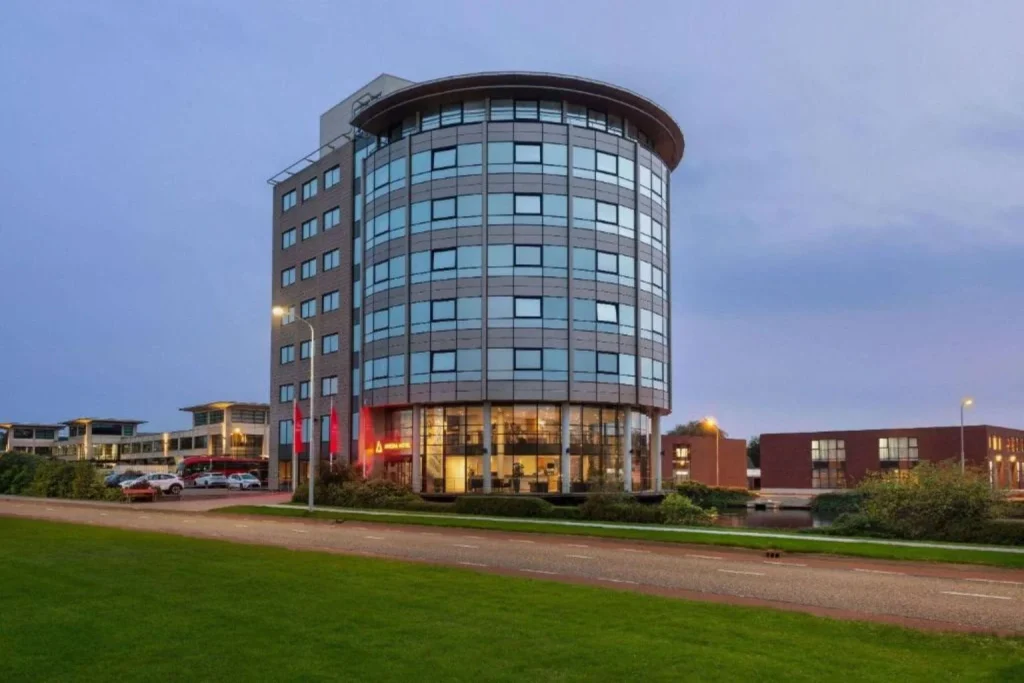 Modern airport hotel exterior with a curved glass facade and illuminated entrance