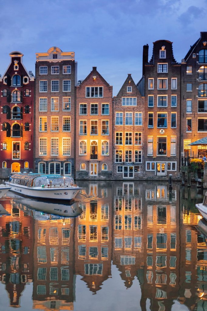 Historic Amsterdam canal houses reflected in the water at dusk