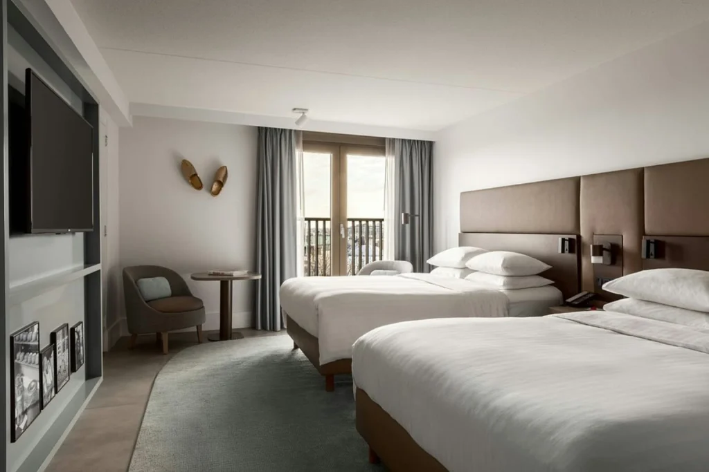 Spacious guest room at Amsterdam Marriott Hotel featuring two large beds, comfortable seating and a bright contemporary interior.