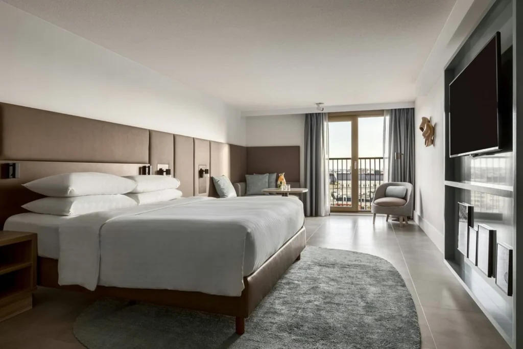 Spacious guest room at Amsterdam Marriott Hotel featuring contemporary interiors, a seating area and a private balcony with views across Amsterdam.