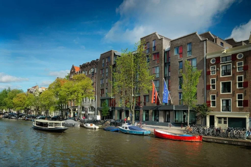 Canal-side view with boats, trees and a mix of historic and contemporary architecture, Andaz Amsterdam Prinsengracht, Amsterdam.