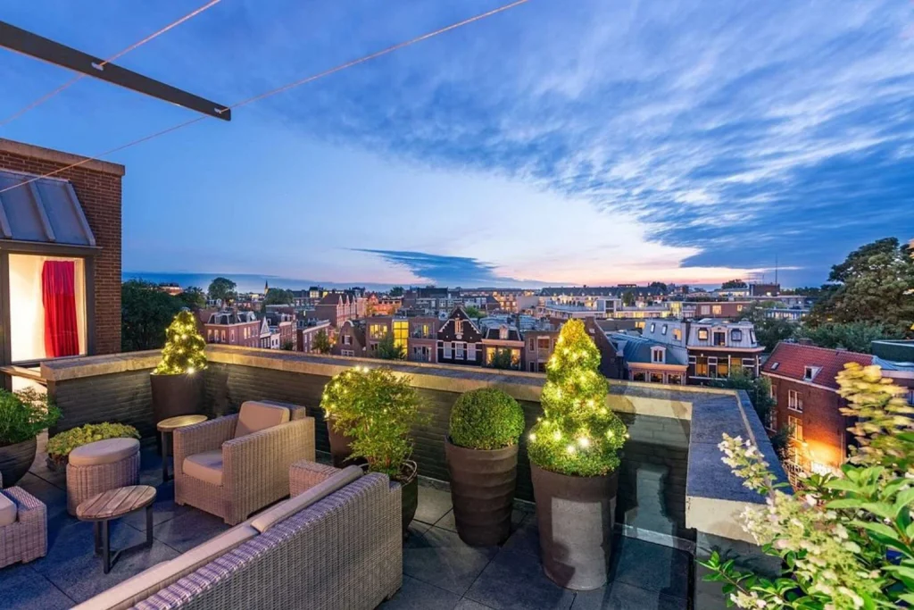 Rooftop terrace at Andaz Amsterdam Prinsengracht offering panoramic views across Amsterdam at sunset.
