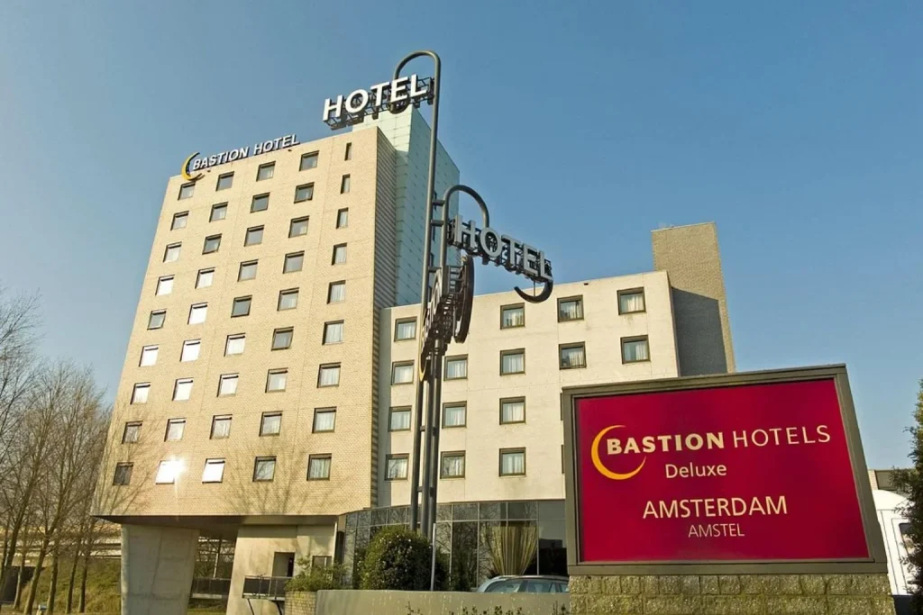Modern multi-story exterior with large windows, prominent hotel signage, and a spacious entrance area in Bastion Hotel, Amsterdam.