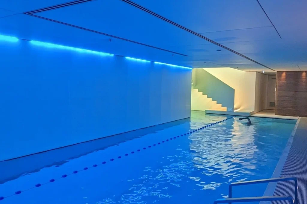 Blue-lit indoor swimming pool with modern minimalist design at Mandarin Oriental Conservatorium, Amsterdam