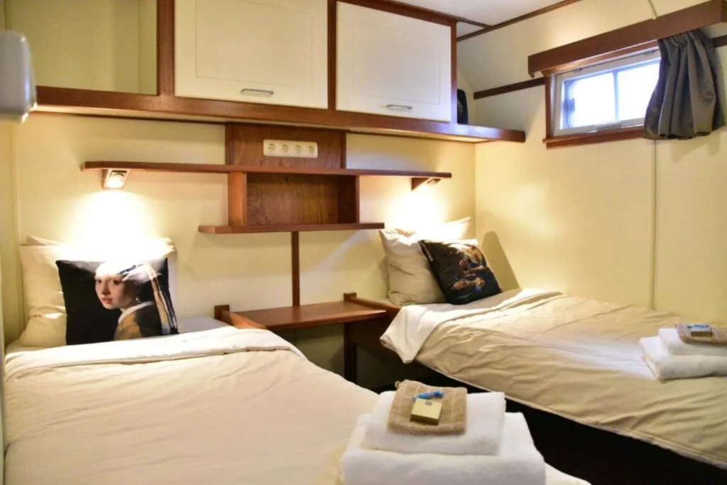 Compact twin cabin with two single beds, warm lighting and nautical-style details at Botel Lena Maria & Similar Canal Boat-Hotels Amsterdam.