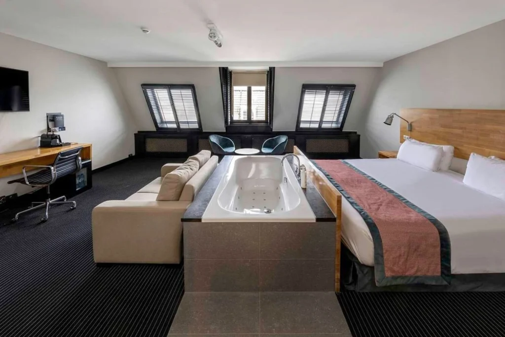 Spacious suite with a king bed, sitting area and private whirlpool bathtub at Catalonia Vondel Amsterdam.