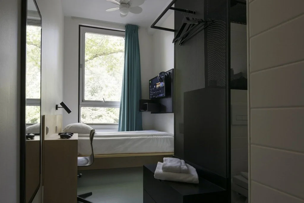 Compact modern guest room with single bed, large window and minimalist interior at De Pijp Boutique Hotel, Amsterdam