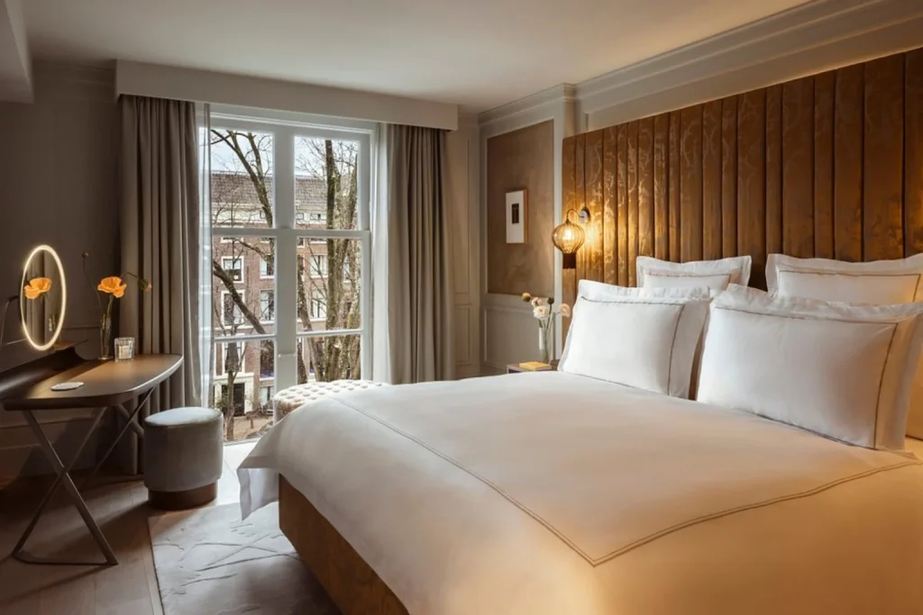 Elegant luxury bedroom with king-size bed, warm lighting and canal-side views at Rosewood Amsterdam, Amsterdam
