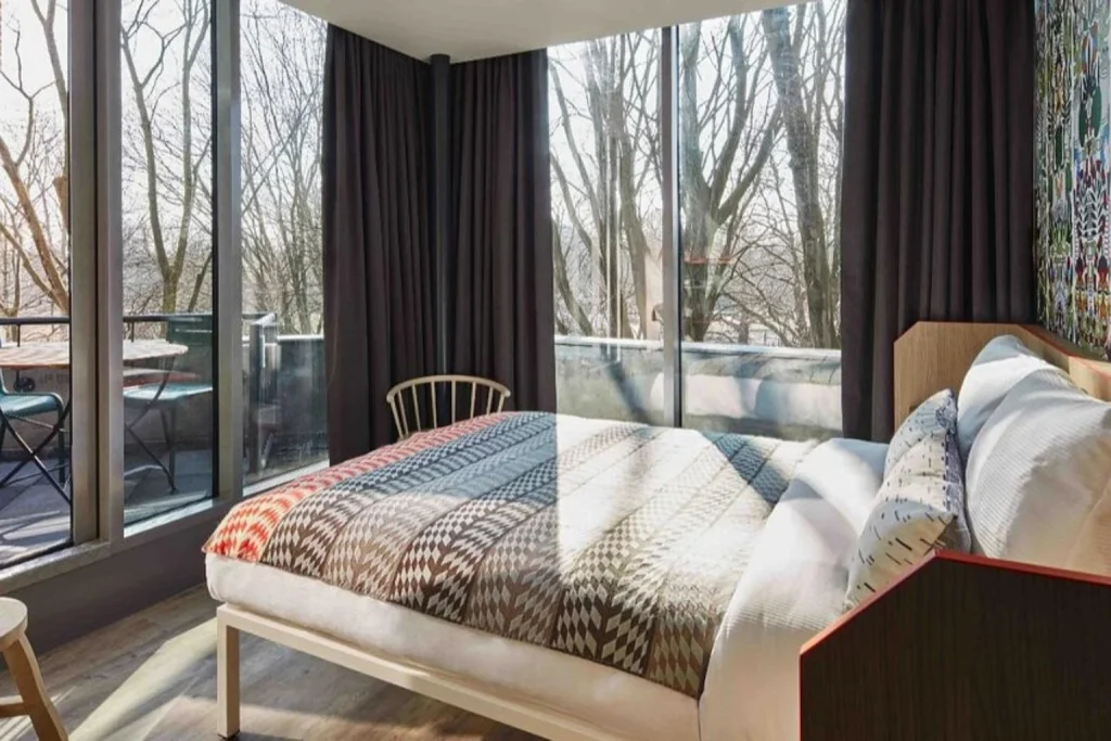 Bright private room with floor-to-ceiling windows and a balcony overlooking Oosterpark at Generator Amsterdam.