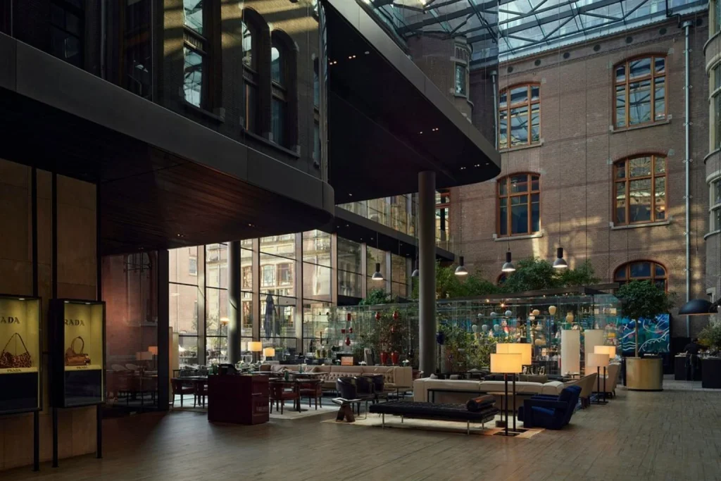 Luxury lobby lounge with glass roof, modern seating and historic architecture at Conservatorium Hotel, Amsterdam