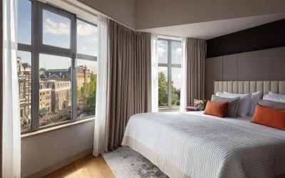 Grand deluxe room with large windows overlooking the city at Anantara Grand Hotel Krasnapolsky Amsterdam in Amsterdam, Netherlands.