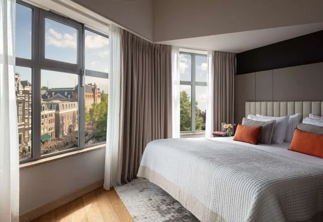 Grand deluxe room with large windows overlooking the city at Anantara Grand Hotel Krasnapolsky Amsterdam in Amsterdam, Netherlands.