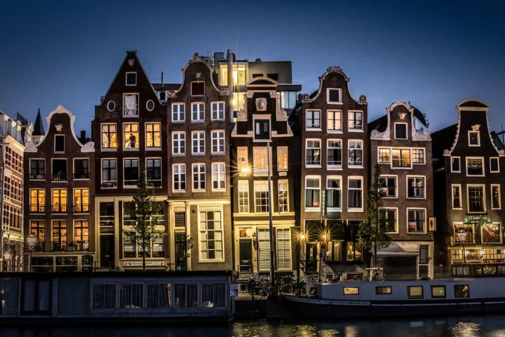 Illuminated historic canal houses and houseboats at night at Hotel Amstelzicht Amsterdam