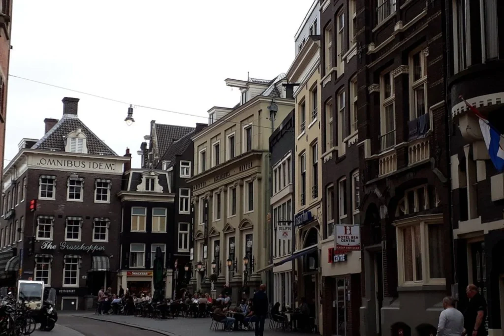 Historic Amsterdam street lined with traditional buildings and cafés near Hotel Ben Centre Amsterdam