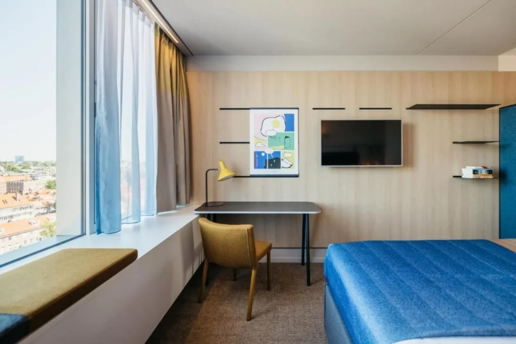 Modern guest room with a work desk and large window overlooking Amsterdam at Hotel Casa Amsterdam.