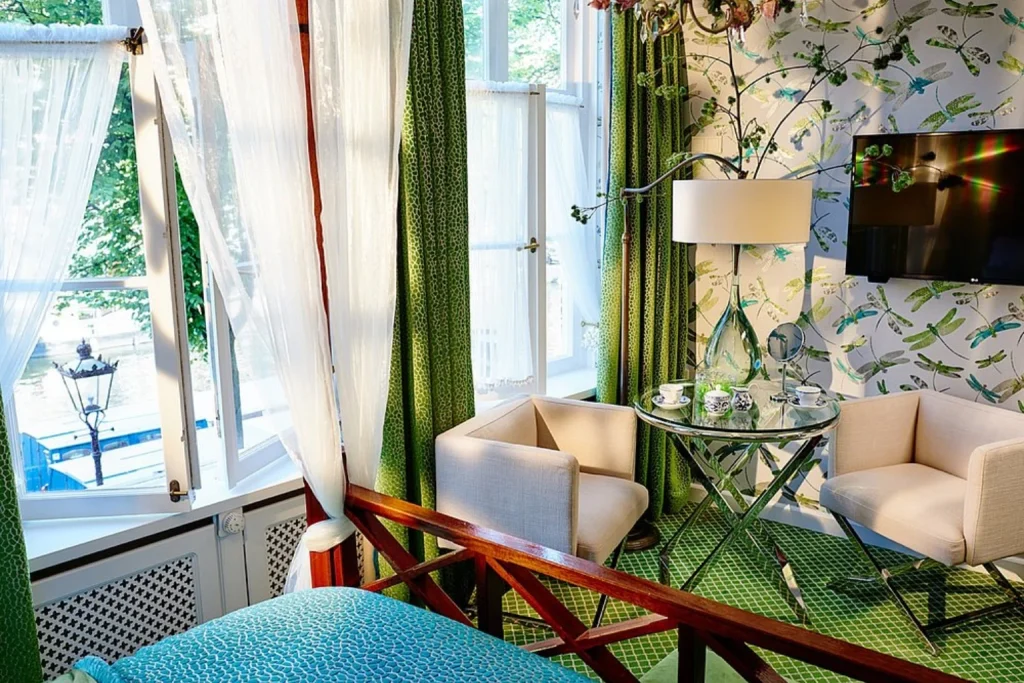 Stylish guest room with vibrant green décor and large windows overlooking the canal at Hotel Estherea Amsterdam.