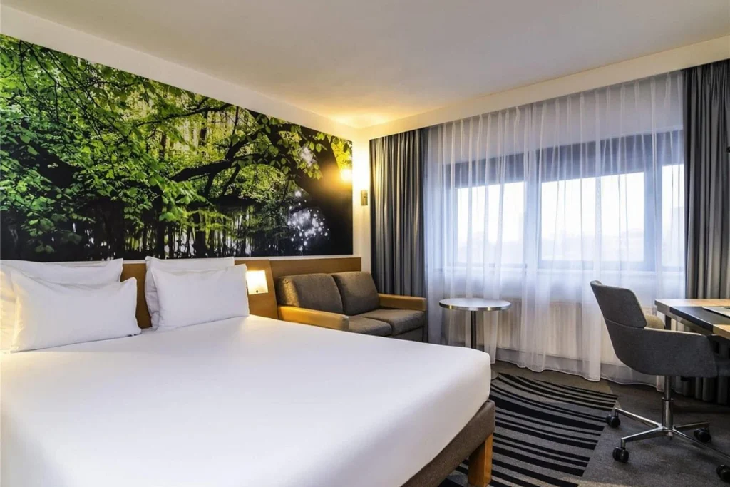 Modern guest room with large bed, seating area and workspace at Hotel Novotel Amsterdam City