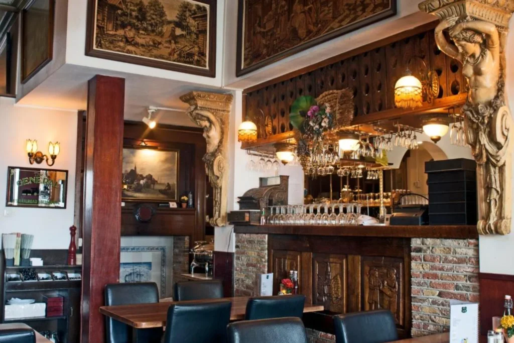 Characterful restaurant and bar featuring carved wood, vintage artwork and traditional furnishings at Hotel Prins Hendrik, Amsterdam.