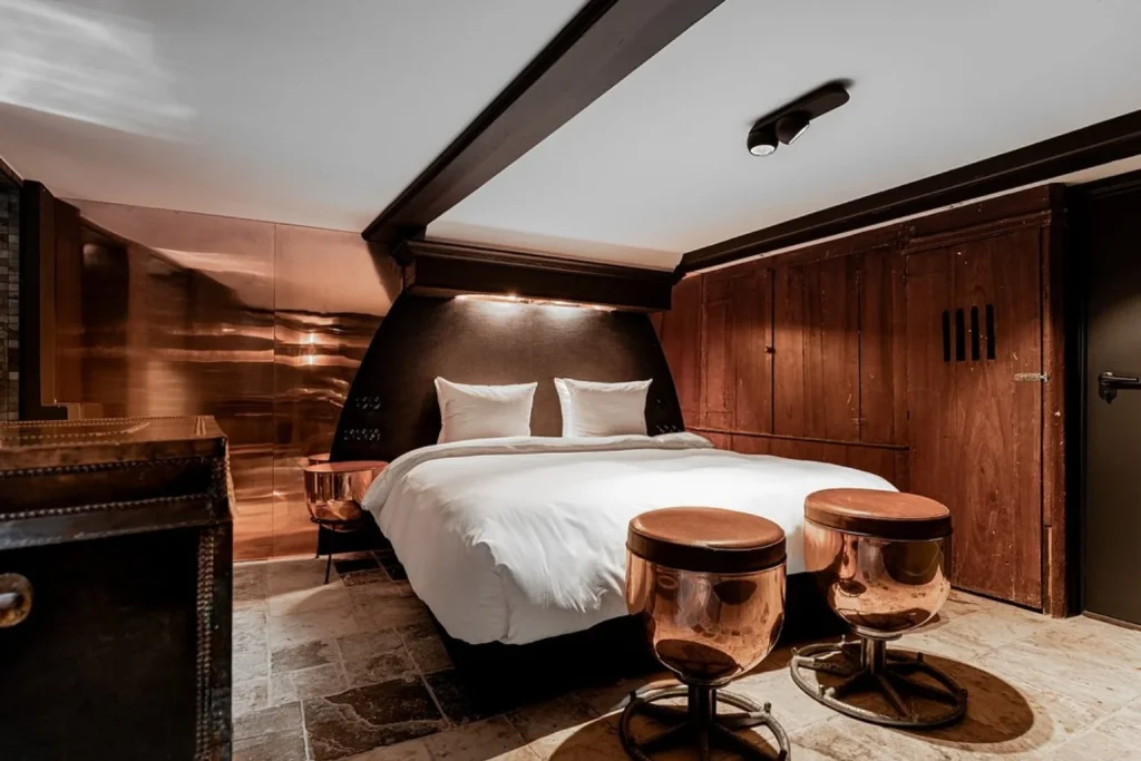 Luxury bedroom with copper furnishings and original wooden details at Hotel The Craftsmen in Amsterdam