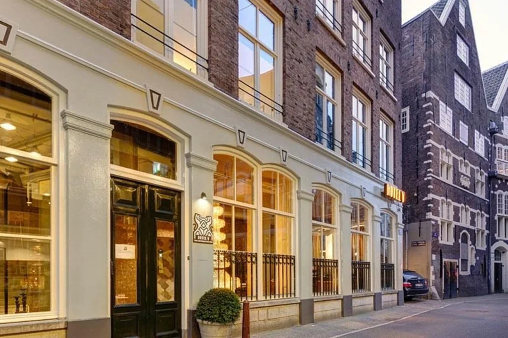 Historic brick facade and entrance on a quiet city street at Hotel V Nesplein Amsterdam