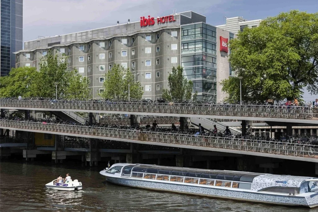 Waterfront hotel building with passing boats and extensive bicycle parking near Amsterdam Central Station at ibis Amsterdam Centre, Amsterdam, Netherlands