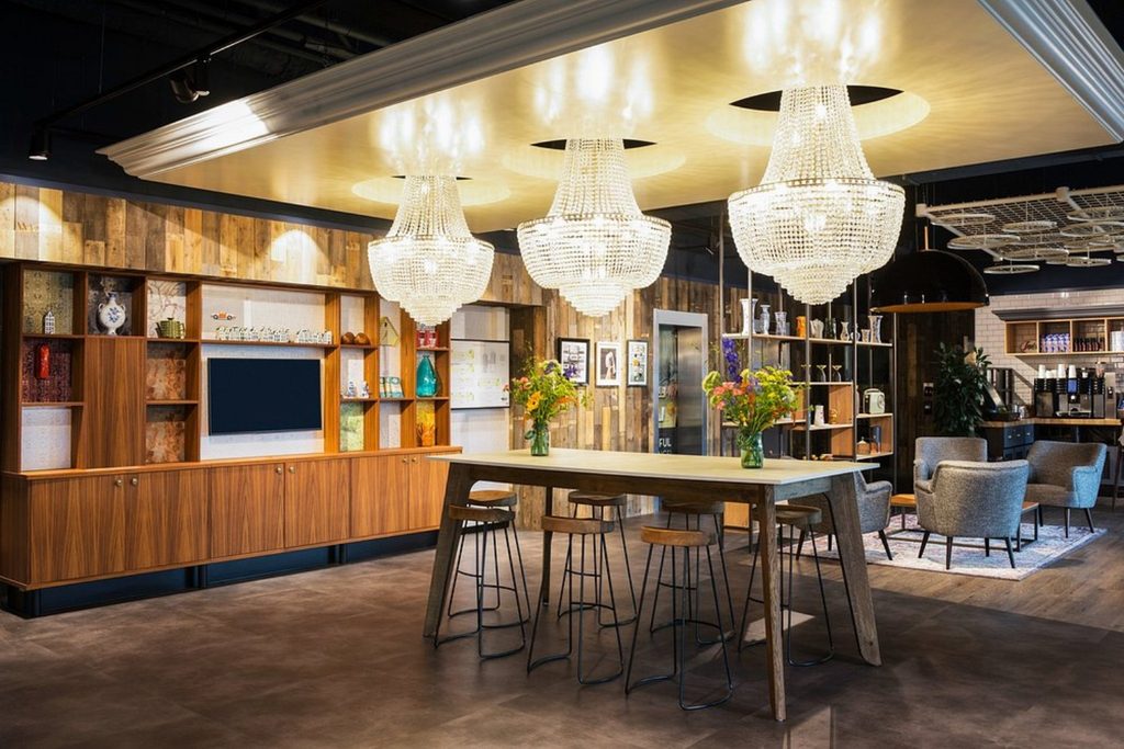 Contemporary lobby with elegant chandeliers, communal tables and comfortable seating at Ibis Amsterdam Centre.
