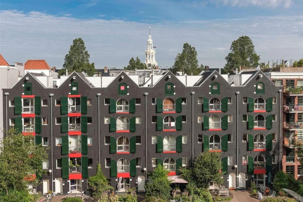 Distinctive dark-brick hotel exterior with green shutters and small balconies, ibis Amsterdam Centre Stopera, Amsterdam