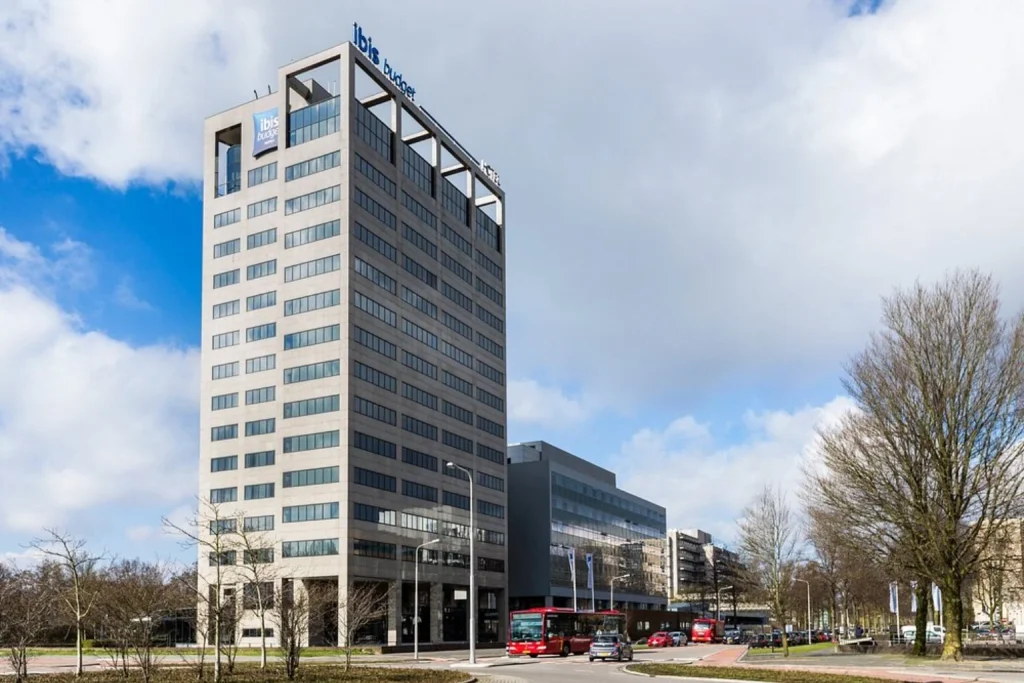 Exterior view of the modern high-rise budget hotel building under a blue sky, Ibis Budget Amsterdam City South, Amstelveen