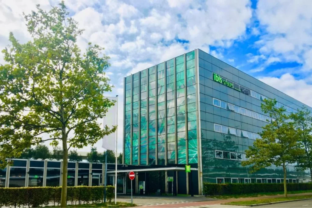 Modern glass-fronted hotel building surrounded by trees near Schiphol Airport at ibis Styles Amsterdam Airport, Amsterdam