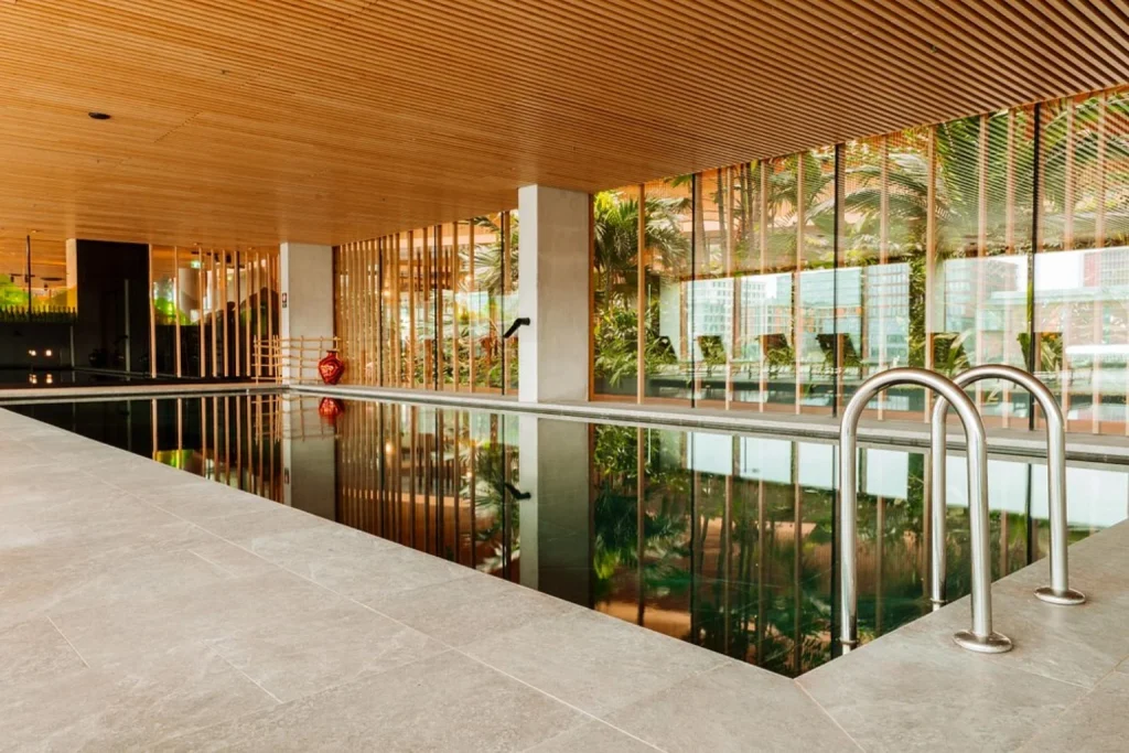 A serene indoor pool framed by tropical plants and contemporary wooden design, Hotel Jakarta Amsterdam