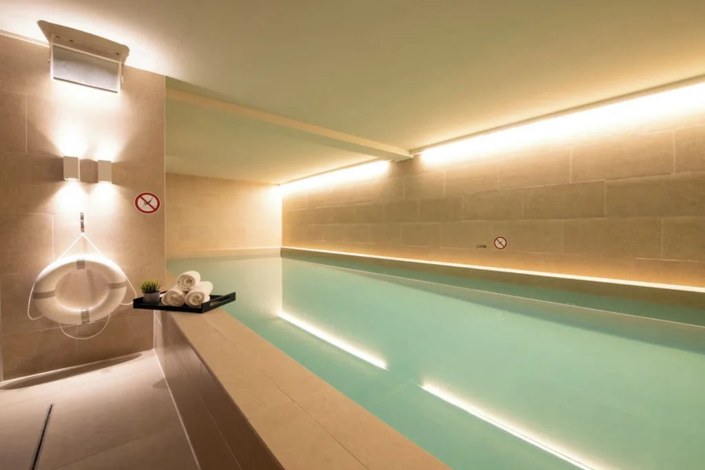 Serene indoor swimming pool with soft lighting and modern stone finishes, Pestana Amsterdam Riverside