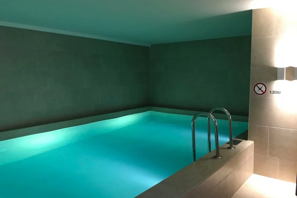 Modern indoor swimming pool with ambient lighting and minimalist spa design at Pestana Amsterdam Riverside, Amsterdam