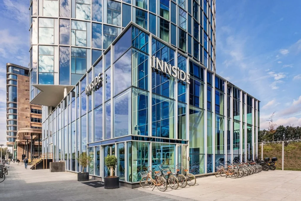 Contemporary glass-fronted hotel building with bicycles outside the entrance at INNSiDE by Meliá Amsterdam, Amsterdam, Netherlands