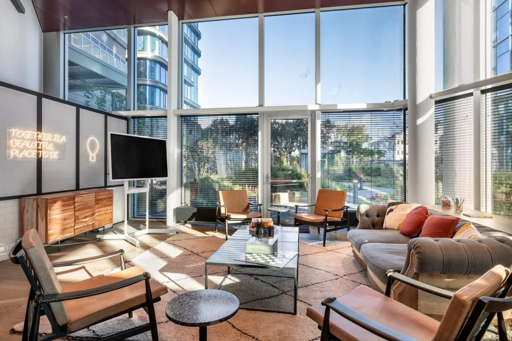 Contemporary lounge with floor-to-ceiling windows, relaxed seating and abundant natural light at INNSiDE by Meliá Amsterdam.