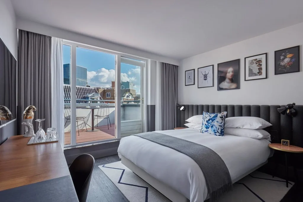 Contemporary guest room at Kimpton De Witt Amsterdam featuring a king-size bed, modern décor and direct access to a private furnished terrace.