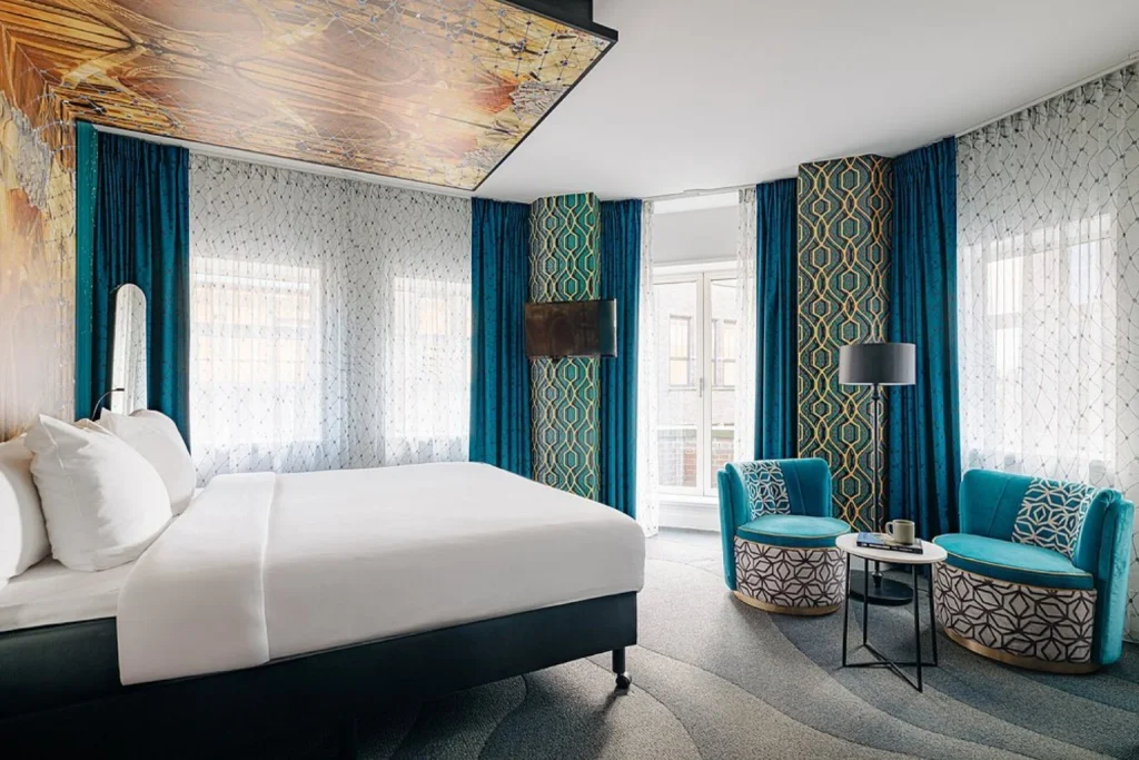 Modern double room with teal seating at Leonardo Eden Hotel Amsterdam City Center