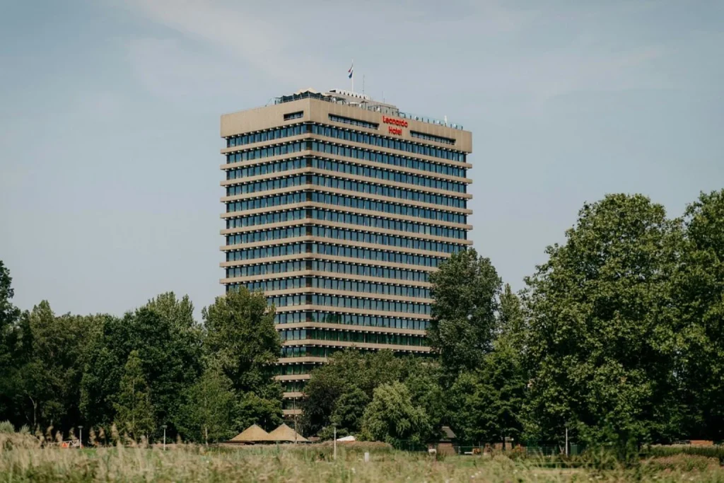 High-rise hotel building rising above the green trees of Rembrandtpark at Leonardo Hotel Amsterdam Rembrandtpark, Amsterdam, Netherlands