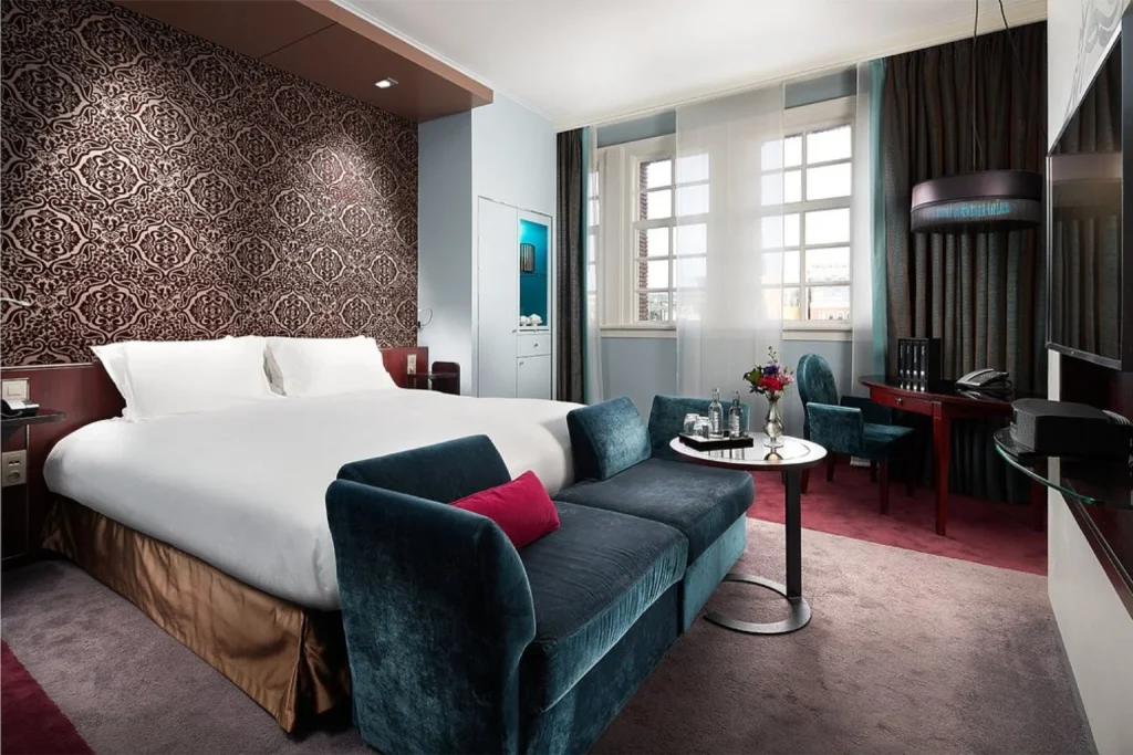 Luxury guest room with patterned feature wall, king bed and velvet seating at Sofitel Legend The Grand Amsterdam, Amsterdam