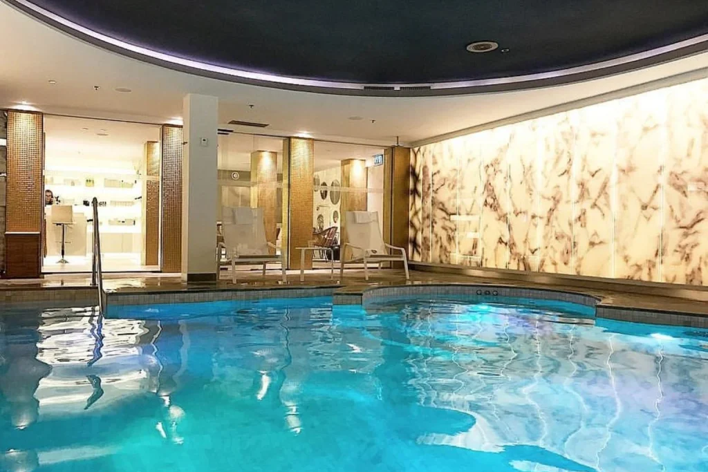 Luxury indoor swimming pool with elegant spa interior and illuminated marble wall at De L’Europe Amsterdam, Amsterdam