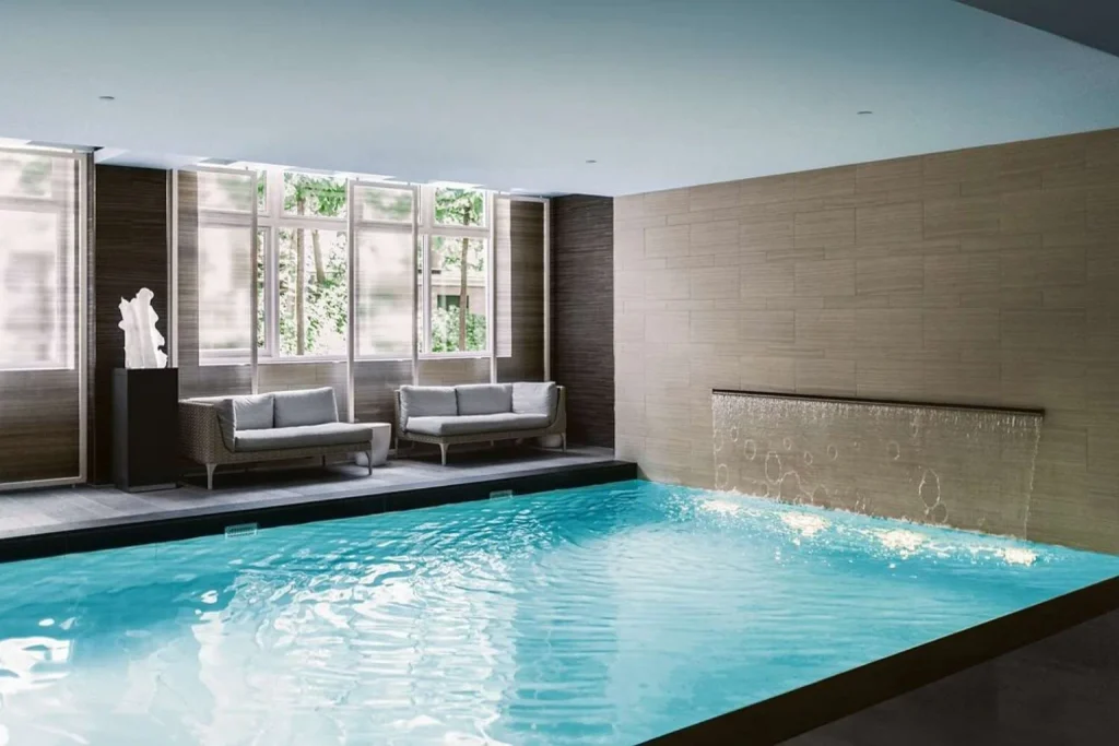 Luxury indoor swimming pool spa with waterfall feature and elegant lounge seating at Waldorf Astoria, Amsterdam