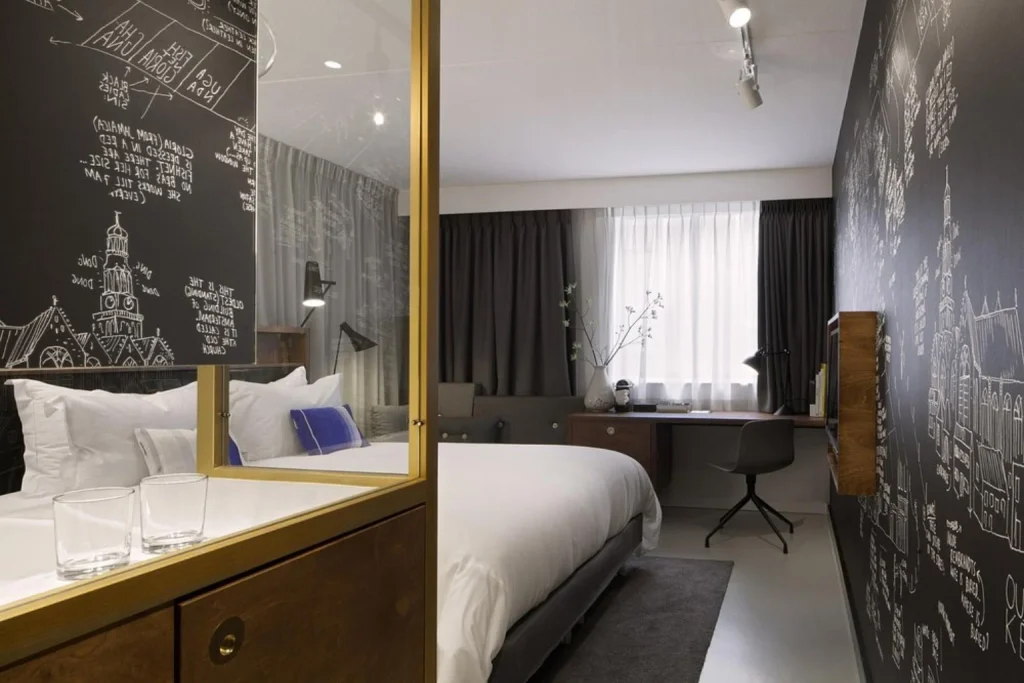 Contemporary guest room with hand-drawn wall graphics, warm wood details and a sleek open-plan design, INK Hotel Amsterdam – MGallery