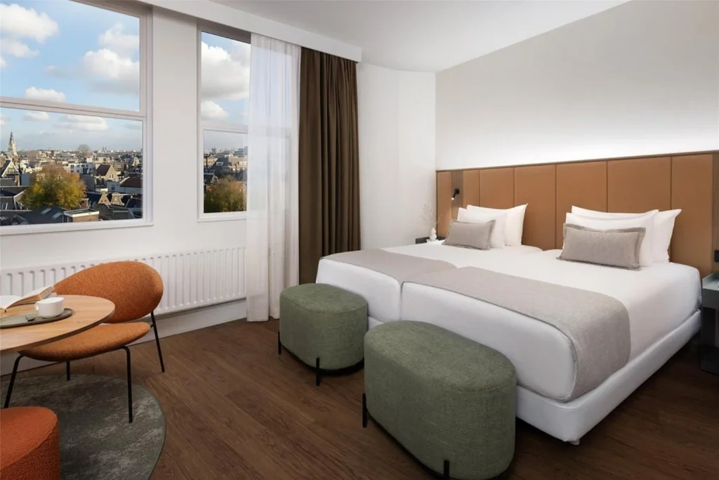 Modern guest room with twin beds, large windows and city views at NH City Centre Amsterdam, Amsterdam