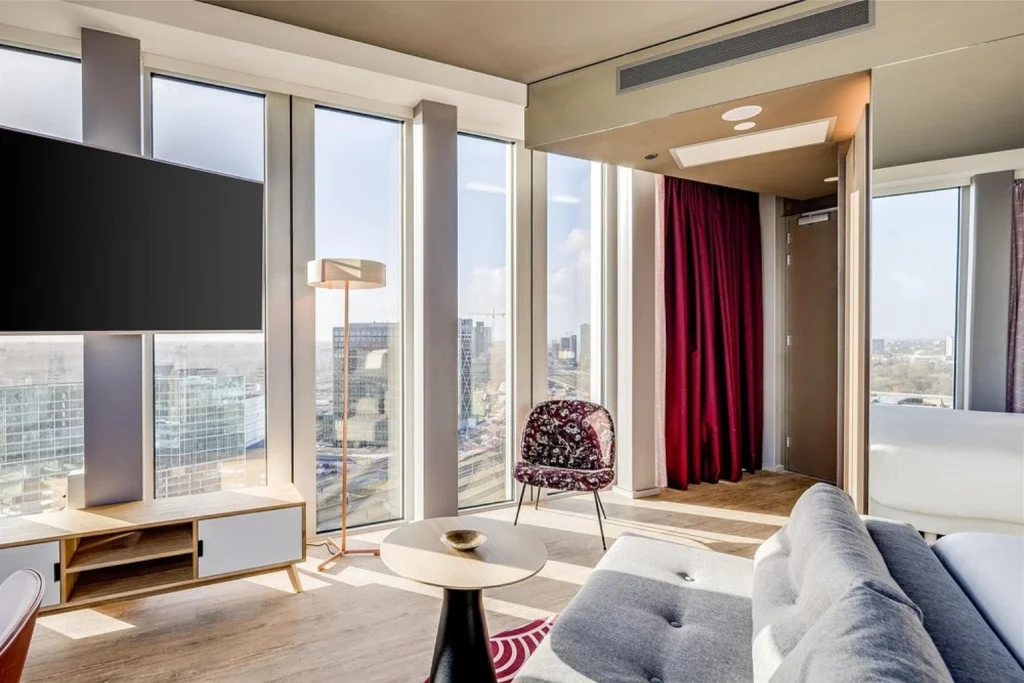 Modern suite with floor-to-ceiling windows and panoramic city views at nhow Amsterdam RAI, Amsterdam