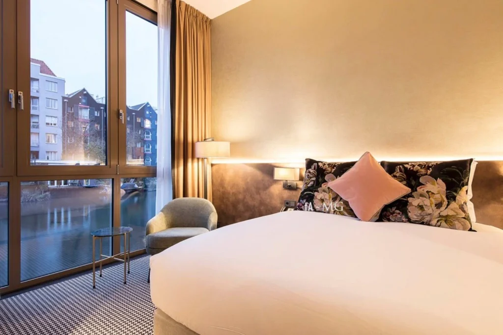 Bright contemporary bedroom with floor-to-ceiling windows overlooking an Amsterdam canal at Monet Garden Hotel Amsterdam.