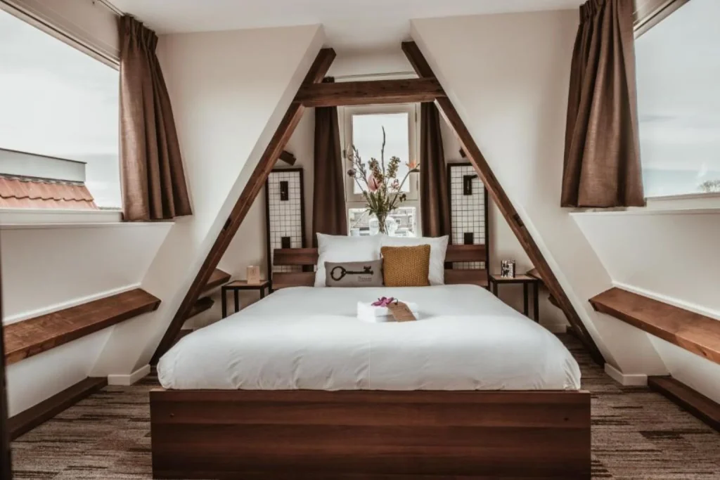 Deluxe double room at Mr Jordaan Hotel in Amsterdam with exposed wooden beams and a cozy bed.