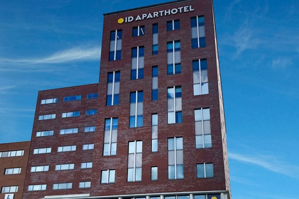 Contemporary red-brick hotel exterior under a clear blue sky at Amsterdam ID Aparthotel, Amsterdam, Netherlands