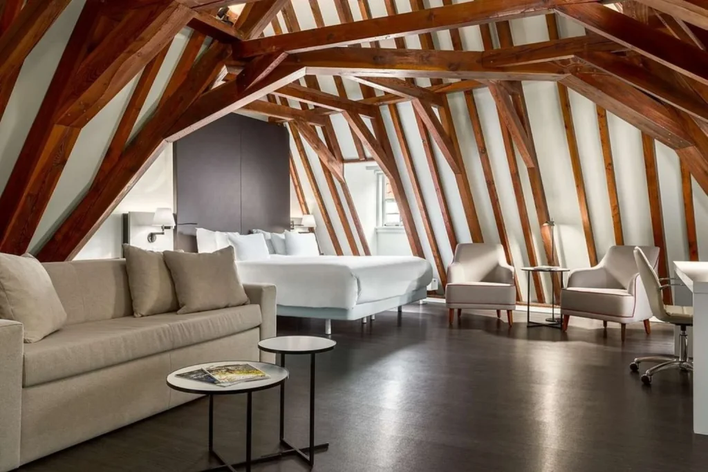 Loft suite with exposed wooden beams and seating area at NH Collection Amsterdam Barbizon Palace in Amsterdam, Netherlands