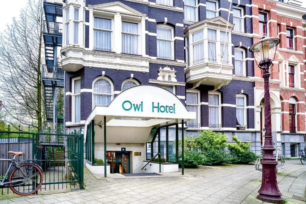 Traditional Amsterdam townhouse with distinctive bay windows and the street-level entrance of Owl Hotel in Oud-West, Amsterdam.