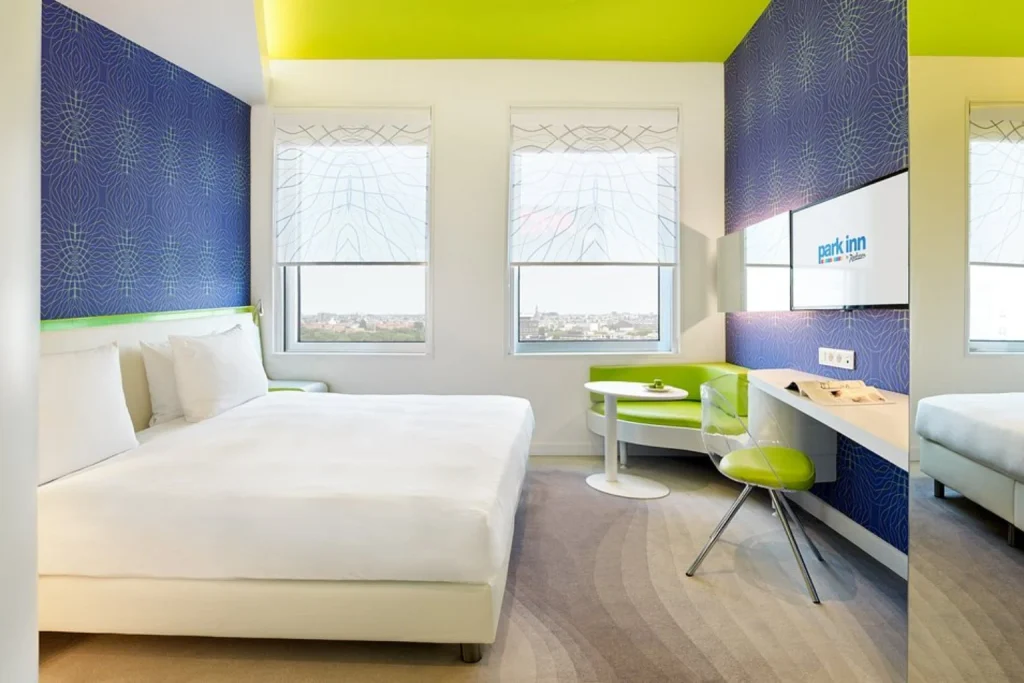 Bright contemporary guest room with city views, colorful accents and a modern seating area at Park Inn by Radisson Amsterdam City West.