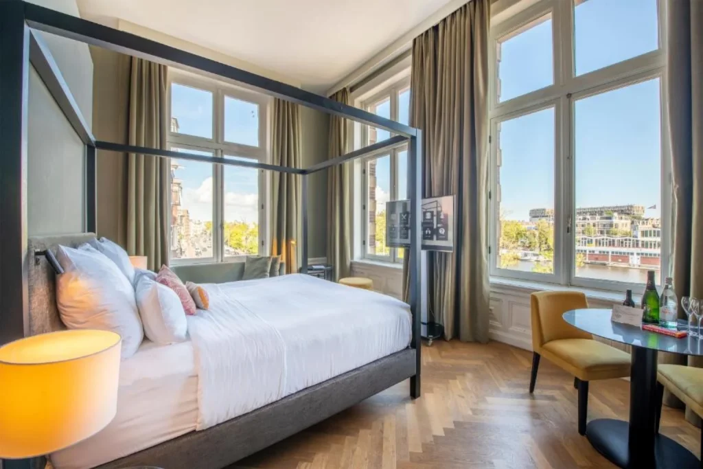 Elegant bedroom with large windows overlooking Amsterdam at Pestana Amsterdam Riverside